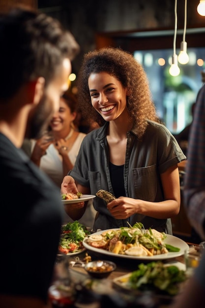 Mulher sorridente servindo comida para amigos masculinos e femininos durante uma festa de jantar em um café