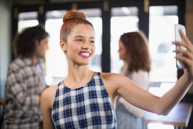 Mulher sorridente tomando selfie no restaurante