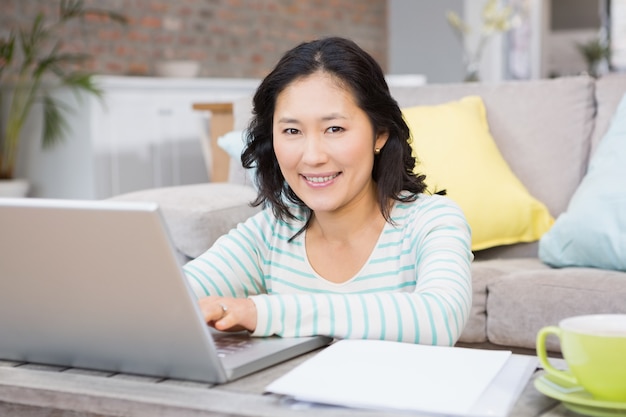 Mulher sorridente, usando computador portátil, em, a, sala de estar