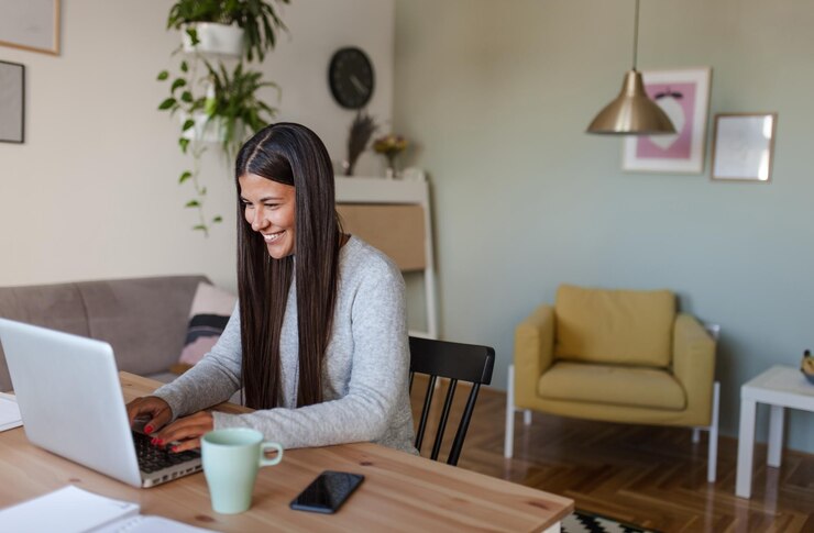 Foto mulher sorridente usando laptop enquanto está sentada no sofá em casa