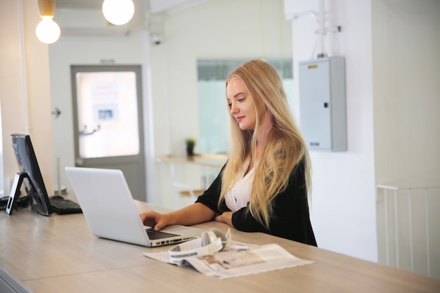 Mulher sorridente usando laptop no local de trabalho para pequenas empresas que procuram envolver o público e dimensionar a criação de conteúdo pode adotar uma nova tecnologia de marketing no local de trabalho. conceito de freelancer.