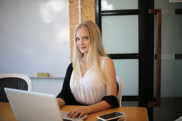 Mulher sorridente usando laptop no local de trabalho para pequenas empresas que procuram envolver o público e dimensionar a criação de conteúdo pode adotar uma nova tecnologia de marketing no local de trabalho. Conceito de freelancer.