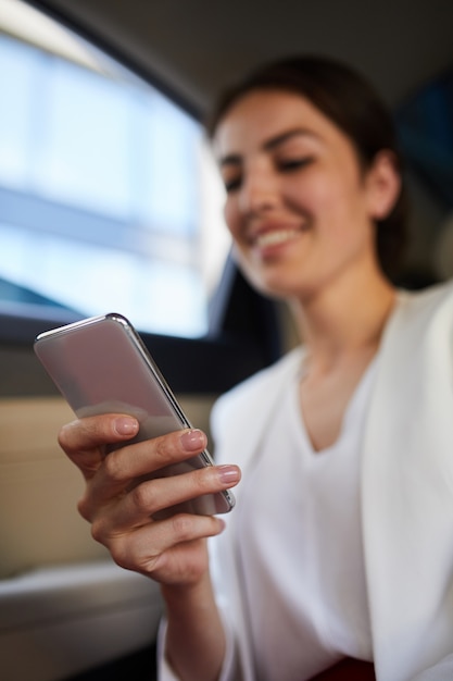 Mulher sorridente usando Smartphone no carro