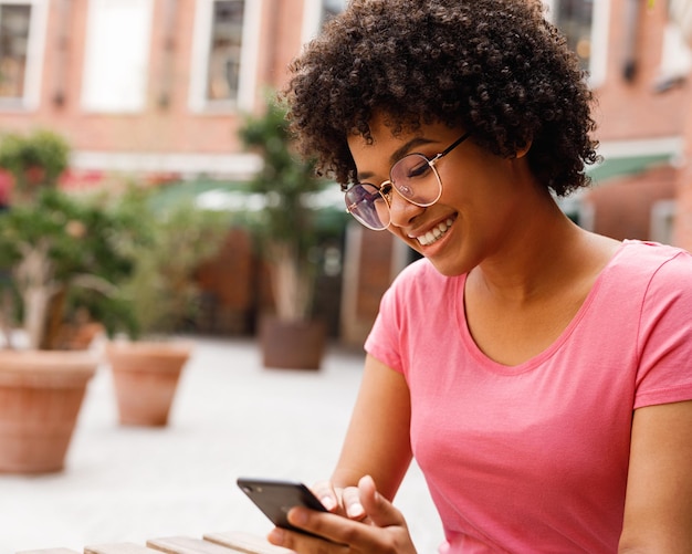 Mulher sorridente usando telefone celular ao ar livre
