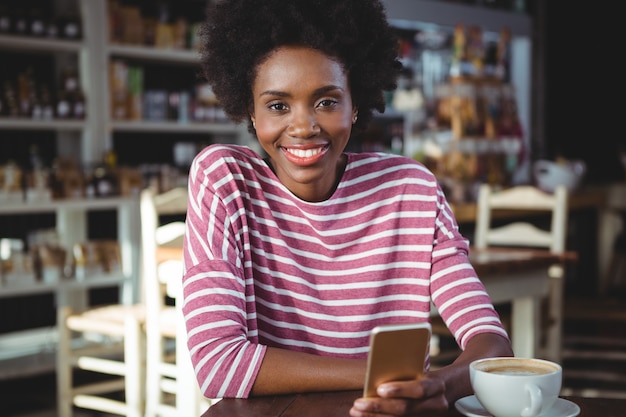 Mulher sorridente usando telefone celular no café