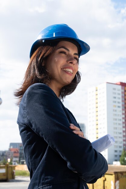 Mulher sorridente usando um capacete enquanto está de pé contra edifícios