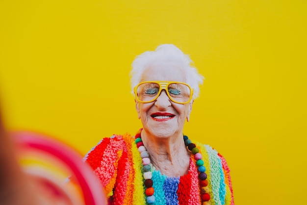 Mulher sorridente vestindo roupas coloridas contra um fundo amarelo