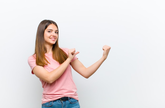 mulher sorrindo alegremente e casualmente apontando para copiar o espaço ao lado, sentindo-se feliz e satisfeito