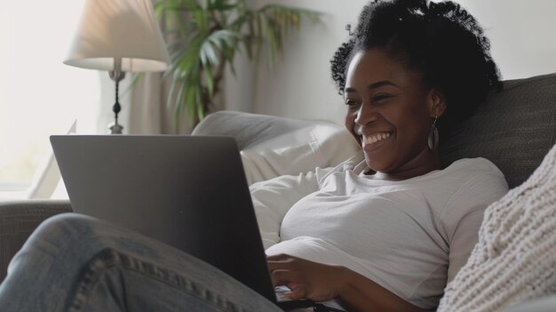 Mulher sorrindo alegremente enquanto usa um laptop confortavelmente descansando em casa