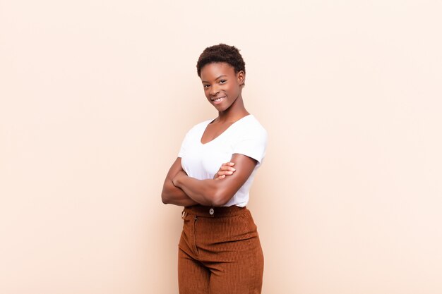 Mulher sorrindo com braços cruzados e uma expressão feliz, confiante e satisfeita, vista lateral