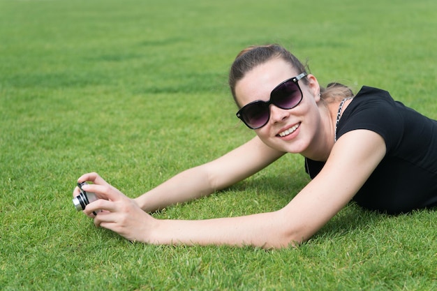 Mulher sorrindo com câmera na grama verde em Paris França