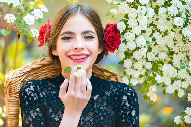 Mulher sorrindo com uma flor branca na boca