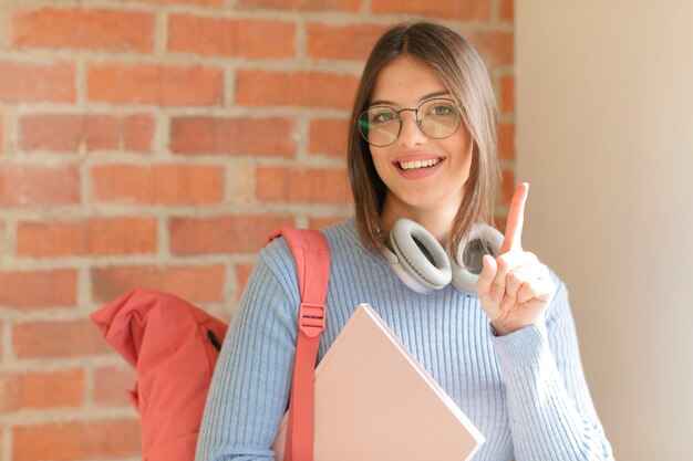 mulher sorrindo e mulher parecendo amigável, mostrando o número um ou primeiro com a mão para a frente, em contagem regressiva