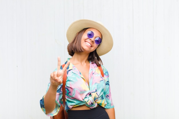 mulher sorrindo e parecendo feliz, despreocupada e positiva, gesticulando vitória ou paz com uma mão