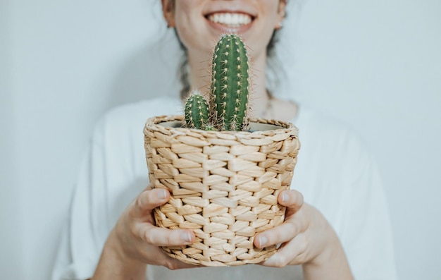 Mulher sorrindo feliz enquanto segura diferentes plantas e cactos para decorar seu novo conceito de casa moderna e elegante copiar imagem do espaço