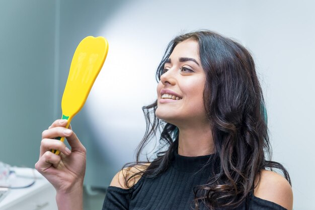 Mulher sorrindo no espelho paciente dental feliz