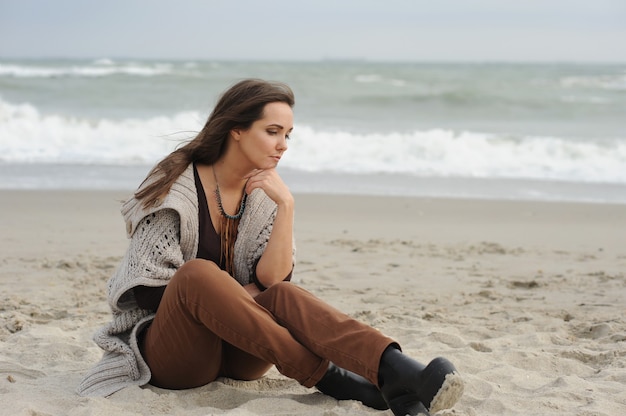 Mulher sozinha e triste sentada em uma praia de mar