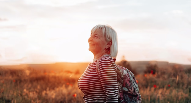 Foto mulher sozinha, levantando as mãos, aproveitando o pôr do sol ao ar livre