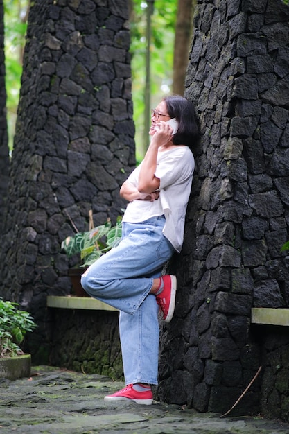 Mulher sozinha no jardim fazendo ligação privada