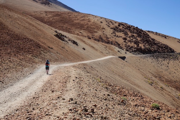 Mulher subindo a estrada de montanha branca para Teide, Tenerife.