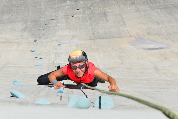 Foto mulher subindo na parede de escalada artificial de uma barragem