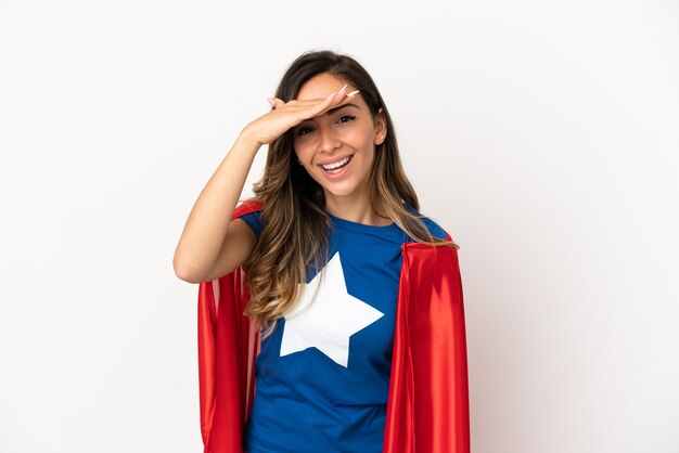 Foto mulher super-heroína sobre fundo branco isolado olhando para longe com a mão para olhar algo