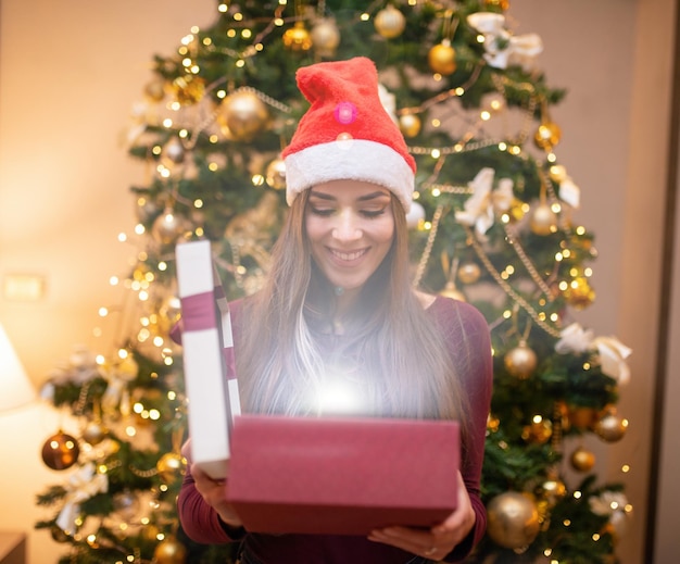 Mulher surpreendida abrindo um presente de Natal