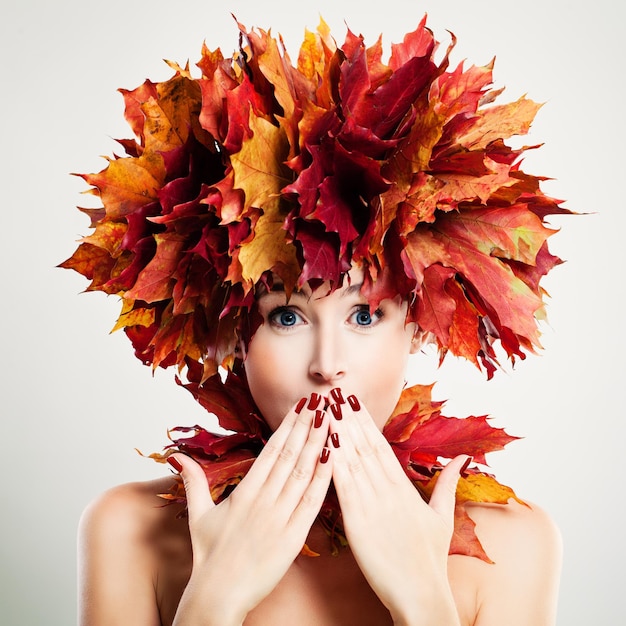 Mulher surpreendida com folhas de outono. Surpresa e diversão