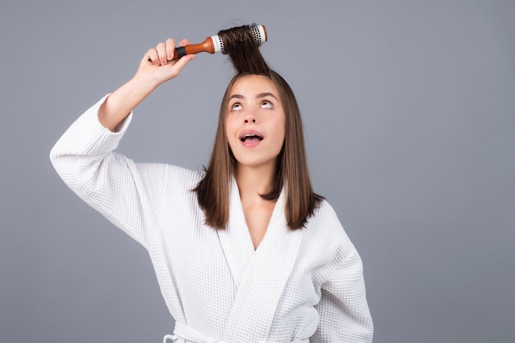 Foto mulher surpreendida penteando o retrato do modelo feminino com um pente, escovando a menina do cabelo com escova de cabelo