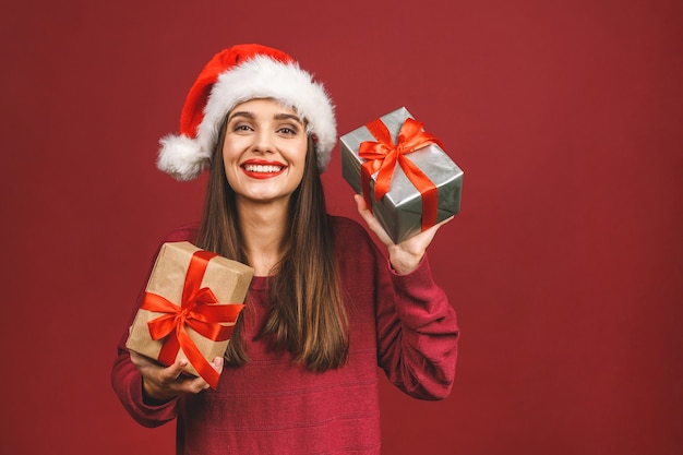 Mulher surpresa e animada com roupa vermelha de Papai Noel segurando um presente