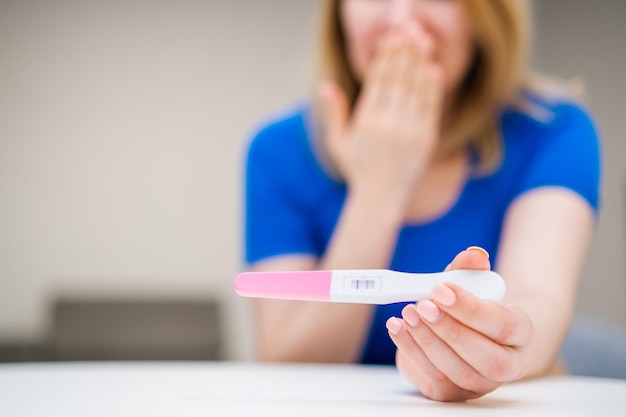 Mulher surpresa feliz segurando um teste de gravidez positivo esperando um bebê