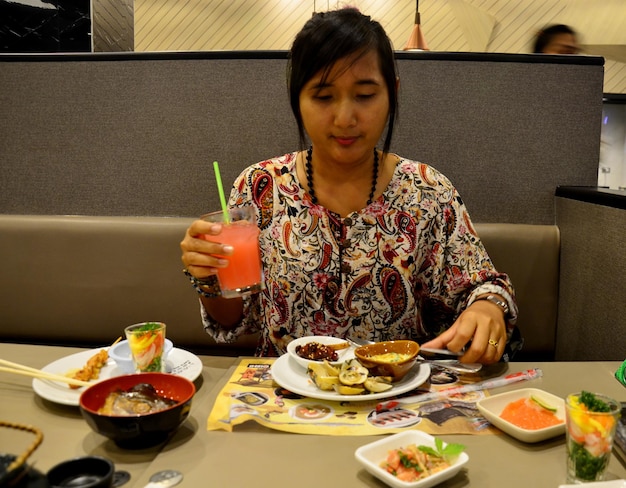 Mulher tailandesa comendo buffet japonês