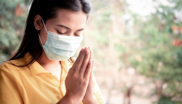 Mulher tailandesa usando uma máscara para proteger o vírus, Covid 19 Orando por bênçãos de Deus para que o mundo esteja a salvo dessa epidemia.