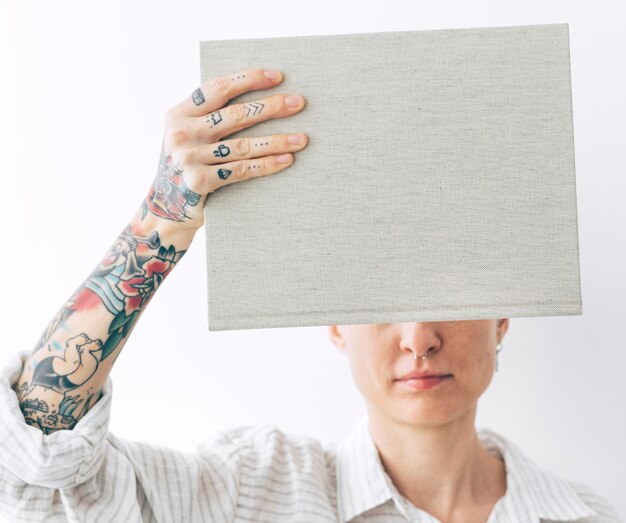 Mulher tatuada segurando uma maquete de livro