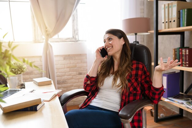 Mulher teletrabalhadora trabalhando em casa com um laptop e smartphone