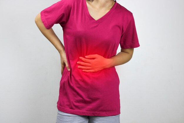 Mulher tem dor de estômago e dor em camisa rosa