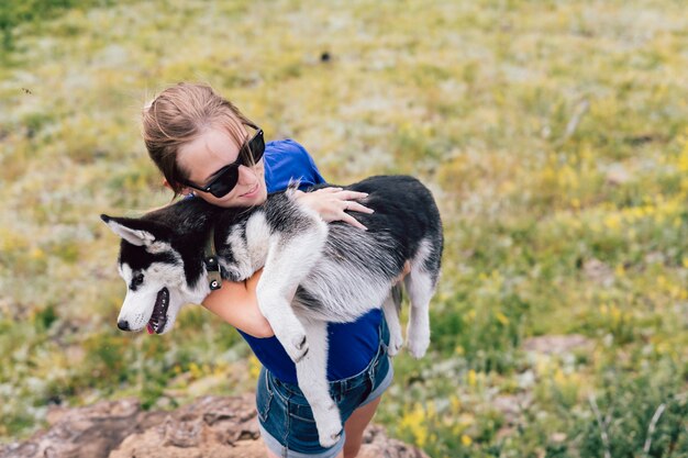 mulher tem um cachorro nos braços. Husky na natureza.