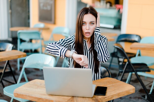 Mulher, tempo verificando, enquanto, sentando, com, laptop, em, café