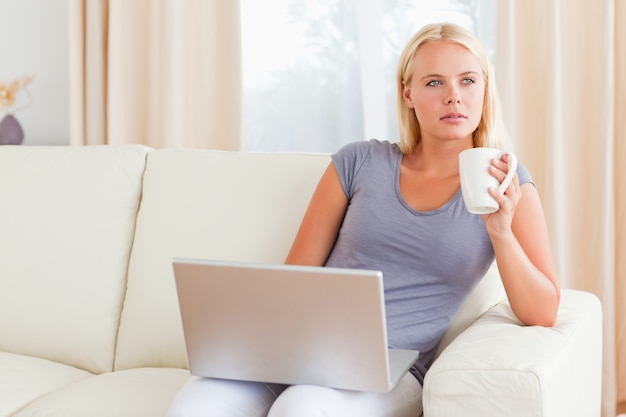 Mulher, tendo um chá, enquanto, segurando, um, laptop