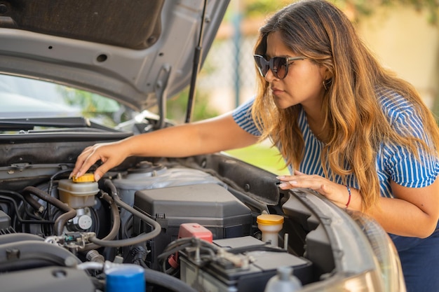 Foto mulher tentando consertar seu motor de carro quebrado