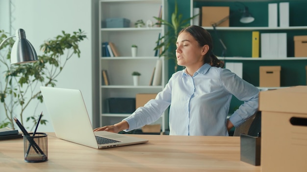 Mulher tentando se levantar da mesa de repente sentindo dor nas costas