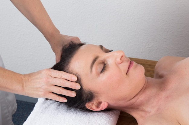 Mulher terapeuta fazendo massagem na cabeça de uma mulher