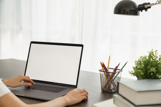 Mulher tinha usando a tela do laptop branco e artigos de papelaria em cima da mesa.