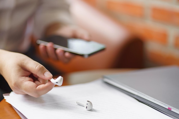 mulher tira fones de ouvido sem fio bluetooth usando smartphone