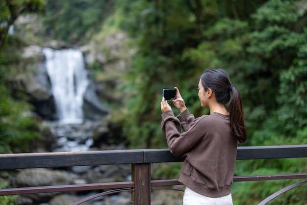 Mulher tira foto com celular na área recreativa da floresta nacional de Neidong, em Taiwan