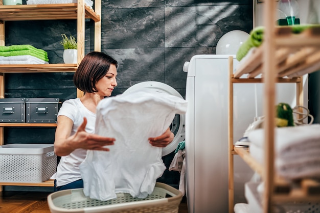 Mulher tirando a roupa na máquina de secar roupa