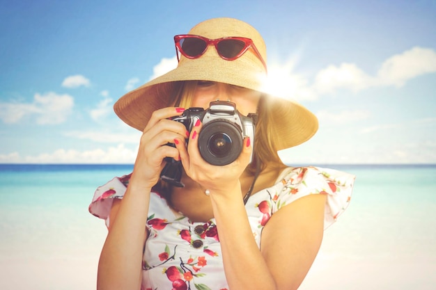 Mulher tirando foto com câmera dslr na praia