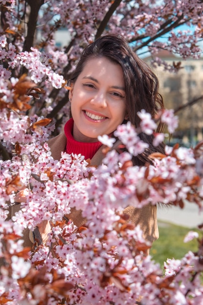 Mulher tirando foto na árvore de sakura florescendo