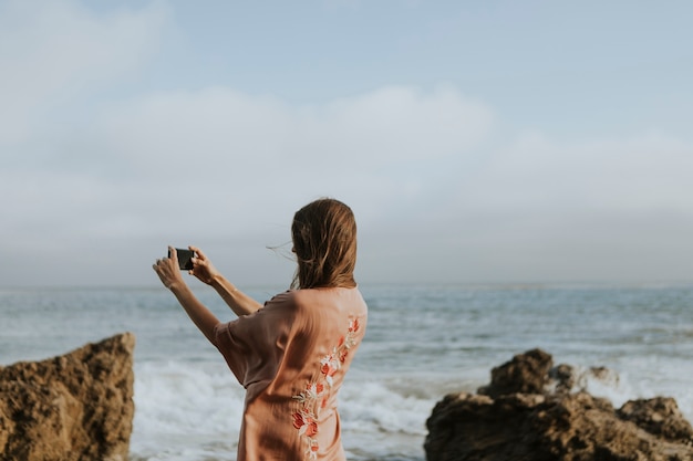 Foto mulher tirando fotos com o telefone na praia