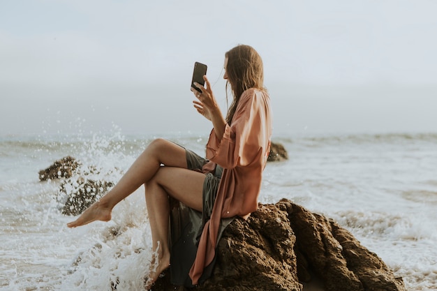 Mulher tirando fotos com o telefone na praia